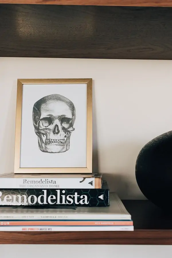 21 Halloween decor Ideas to Unleash your Creativity - Decor Hint skull picture in a gold frame on a bookshelf