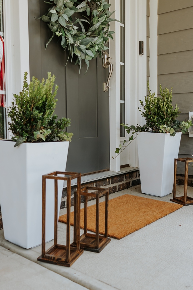 white painted outdoor planters with greenery in them and wood lanterns