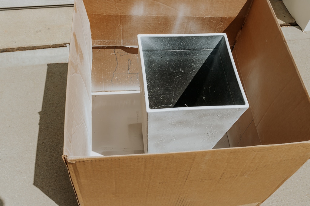 white plastic planter pot being spray painted - how to paint outdoor planters - full tutorial in post