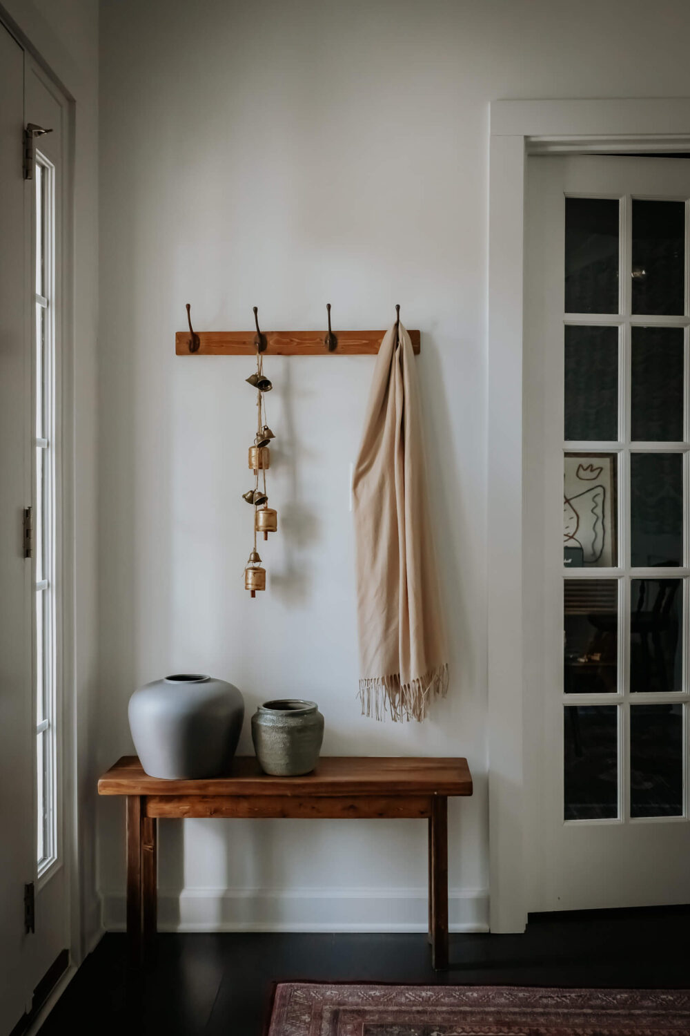 Entryway with a bench and a coat rack and a red vintage style rug
