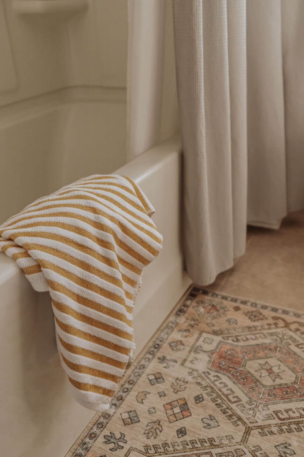 How to Wash Towels With Vinegar (and Why you Should) - Decor Hint fresh towel draped over the side of the tub - in post, how to wash towels with vinegar