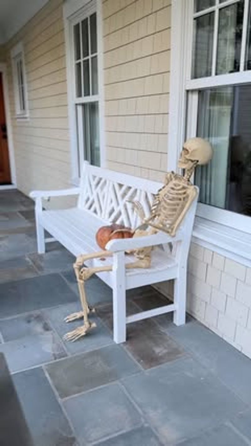 Skeletons On The Porch Bench Holding Trick-Or-Treat Bags