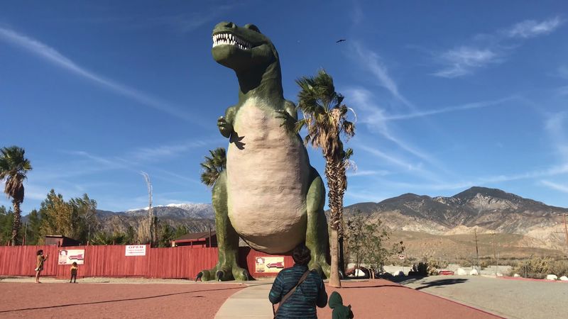 Two Giant Dinosaurs Watch Over The Freeway
