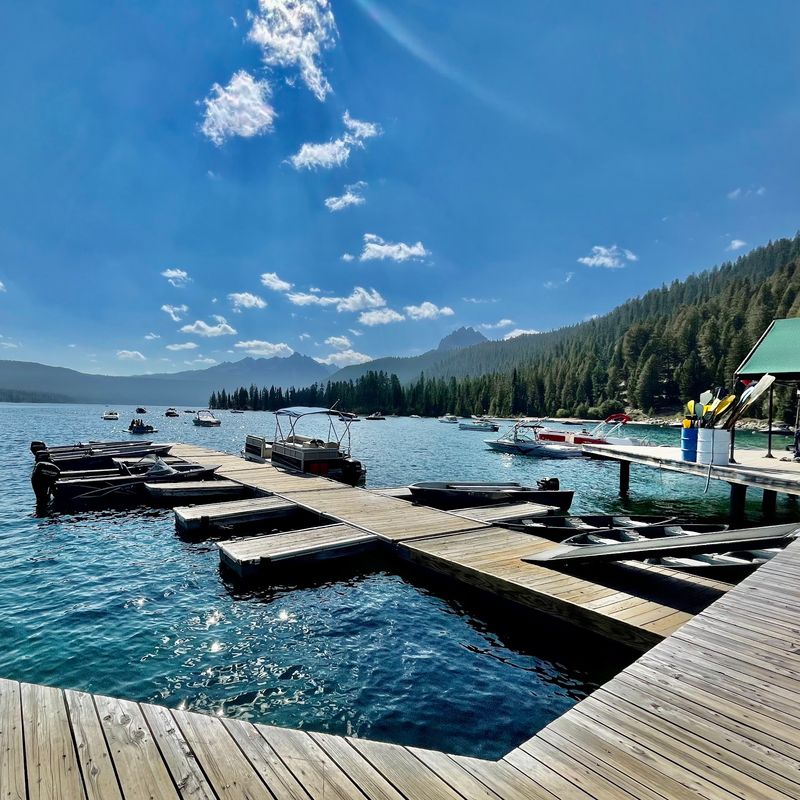 This Idaho Lodge Offers Rustic Cabins Right On The Water, With Mountains All Around - Decor Hint Boats, Kayaks, And Canoes Lined Up Right Out Front