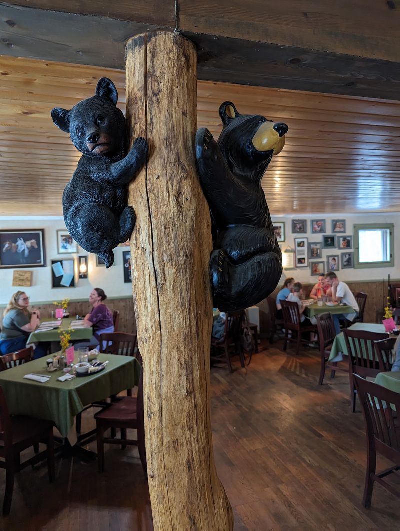 Green Tablecloths, Flowers, And A Carved Bear Keep Watch